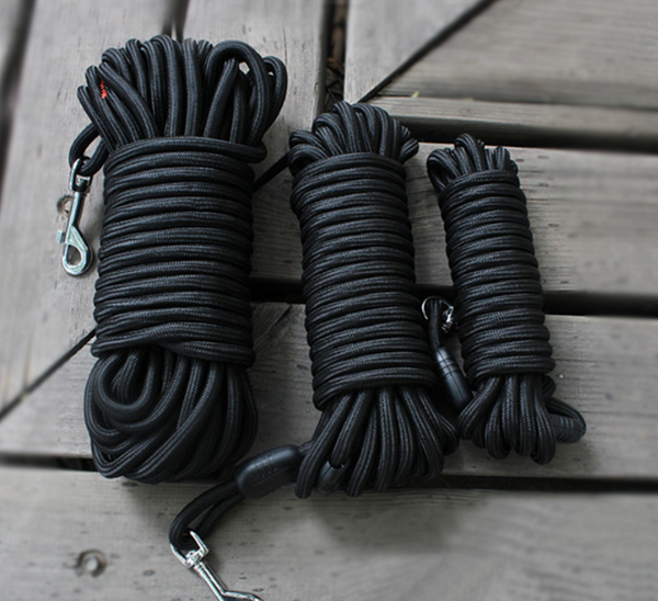 Three coiled black Field Long Line Leash ropes in different lengths with metal clips, on a deck