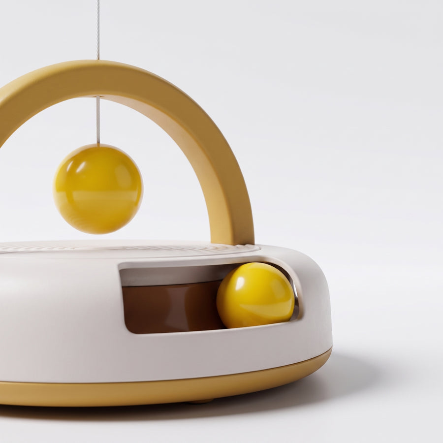 Close-up detail of the Eddy Gravity Feather Spinner showing the hanging yellow ball on its string and the yellow ball inside the brown track window of the white base