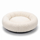 Halo Round Cushion Bed shown from a three-quarter rear angle, ivory plush sherpa donut bed with dark base, on white studio background