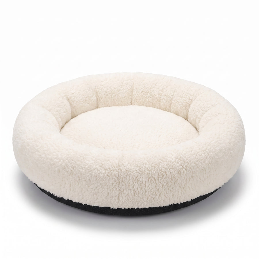 Halo Round Cushion Bed shown from a three-quarter rear angle, ivory plush sherpa donut bed with dark base, on white studio background