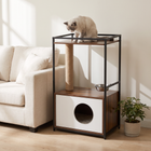 A cat sits on the railed top shelf of the FELVO Hearth cat tree, above its sisal scratching post, stainless steel bowl and enclosed condo